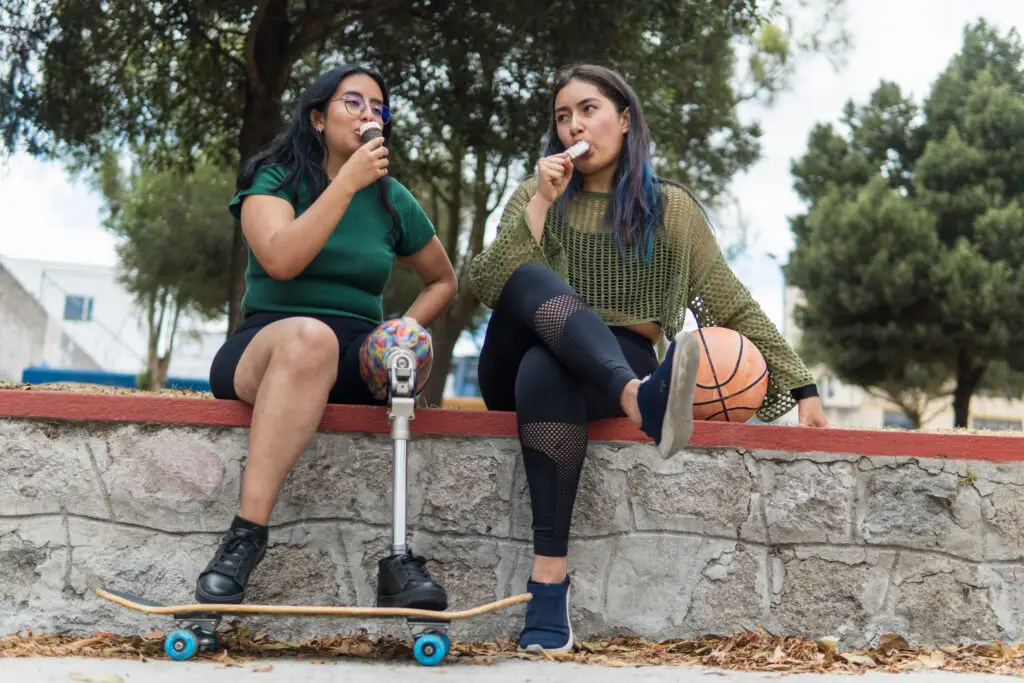 Two young latin women with disability enjoying ice cream in a park